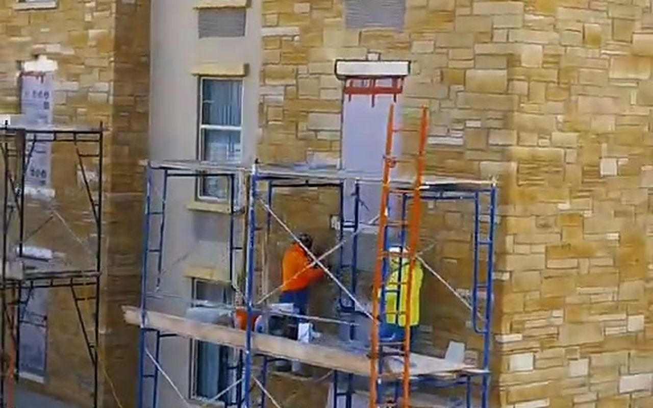 Texas Pro mason working from a scaffold tower on the stone facade of the Drury Inn in Amarillo